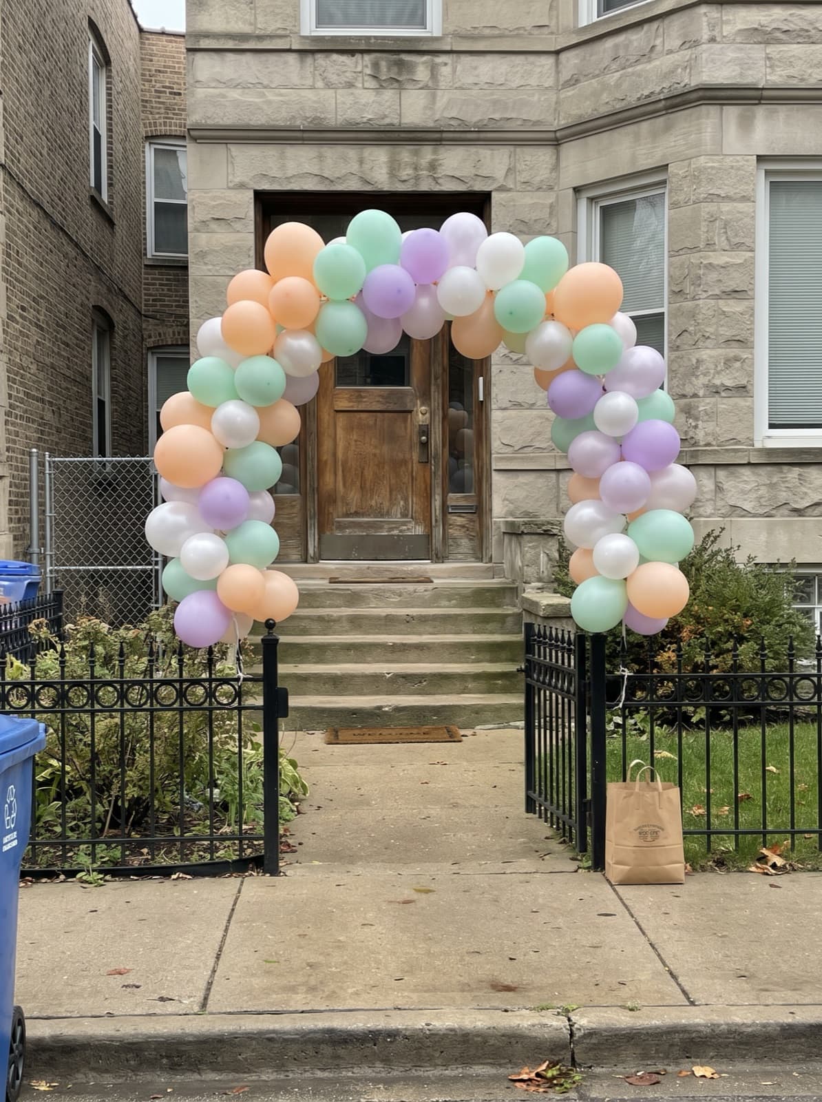 Pastel balloon arch over the front steps of a greystone two-flat