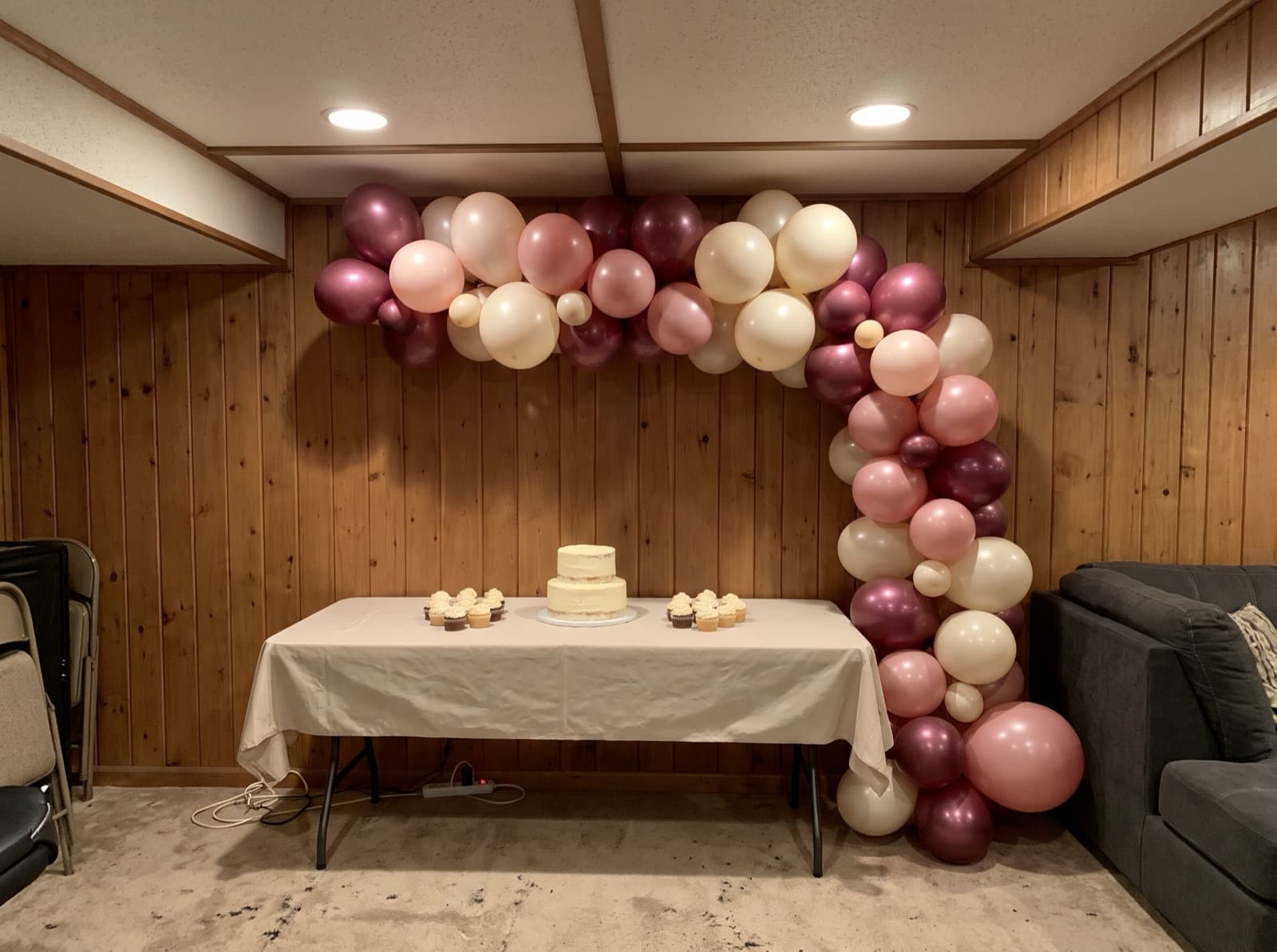 Organic balloon arch in burgundy, blush and cream over a dessert table in a basement party room