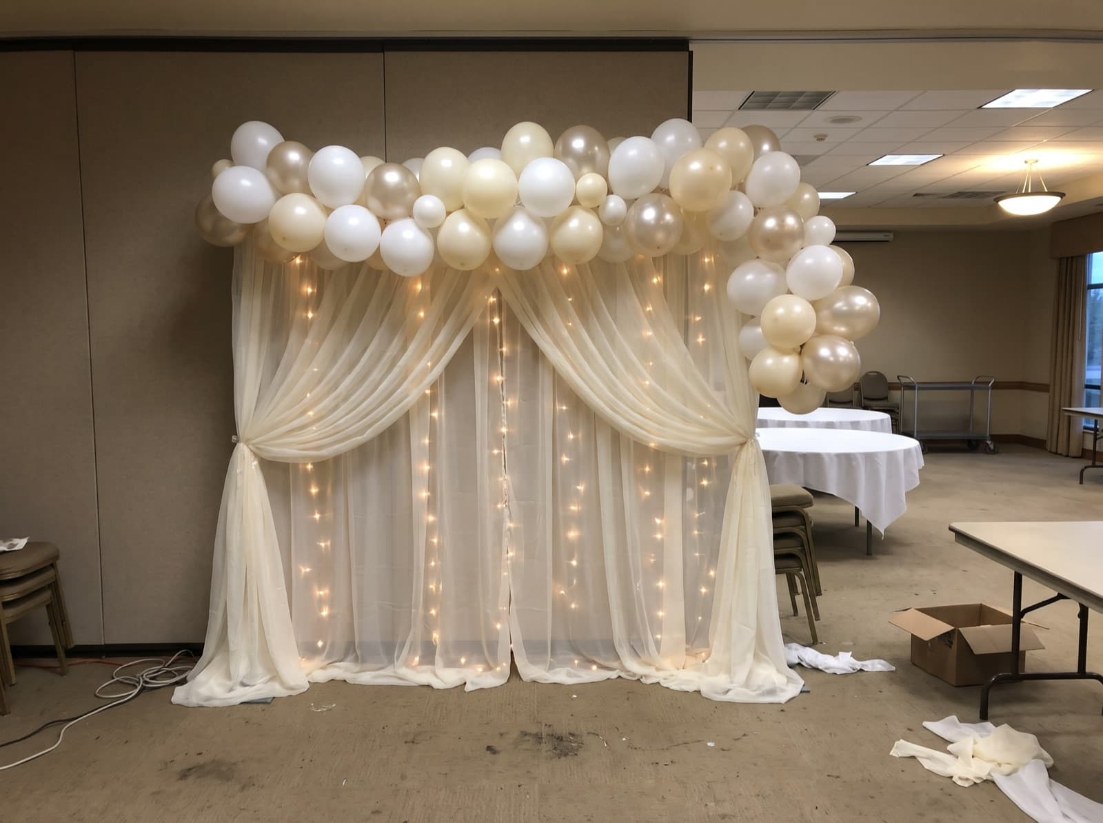 Ivory draped backdrop with lights and a white and champagne garland
