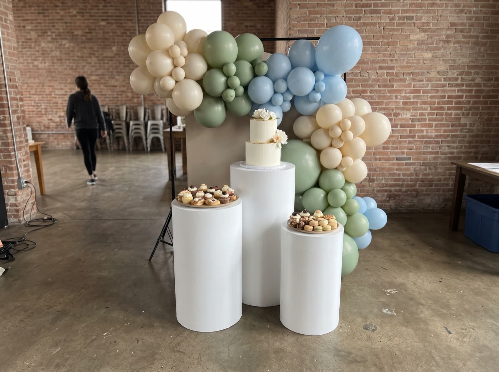 Backdrop with white pedestals holding a cake and desserts