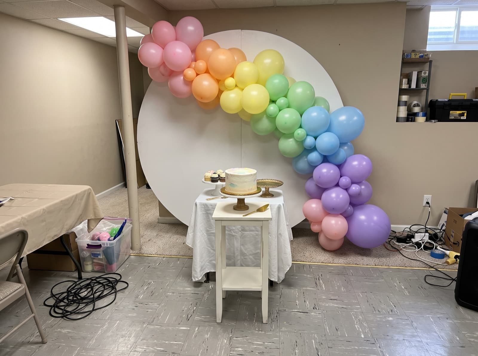 Round white backdrop with a pastel rainbow balloon garland