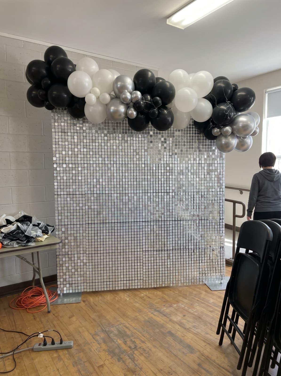 Silver shimmer wall backdrop with a black, white and silver balloon garland