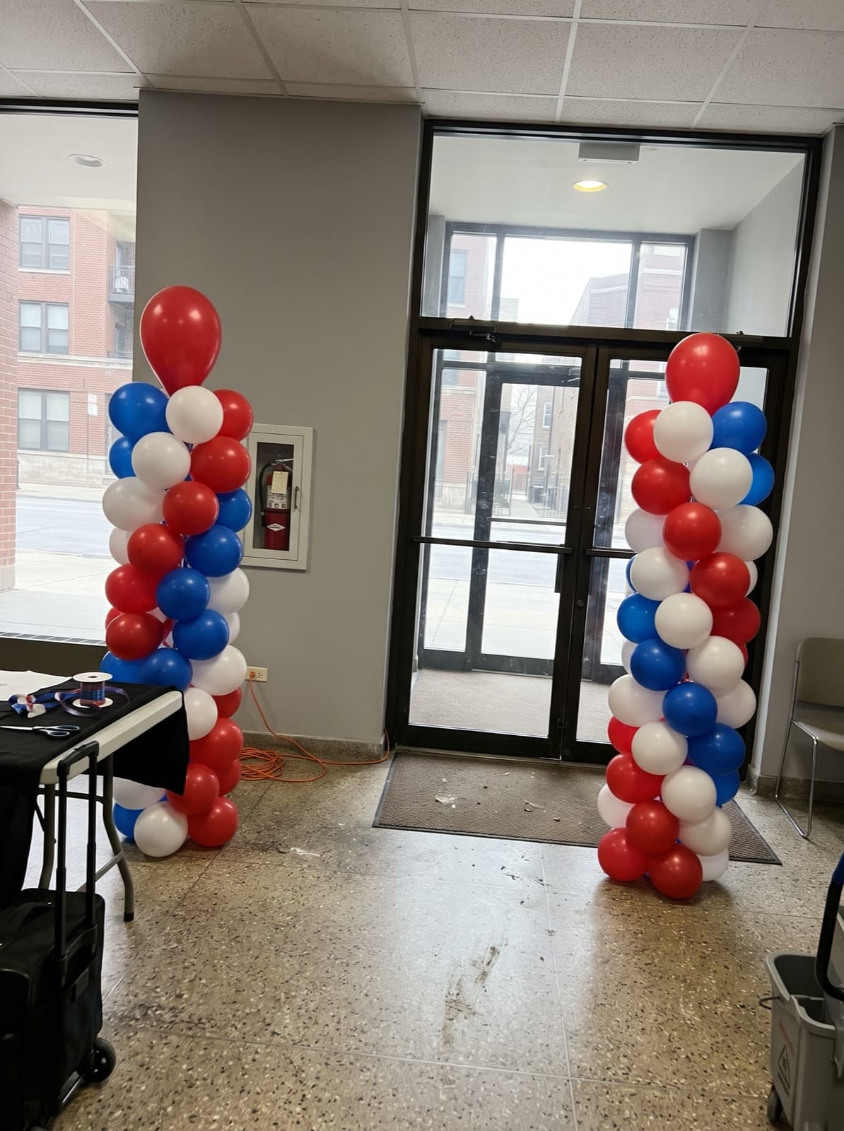 Red, white and blue spiral balloon columns at an office lobby entrance