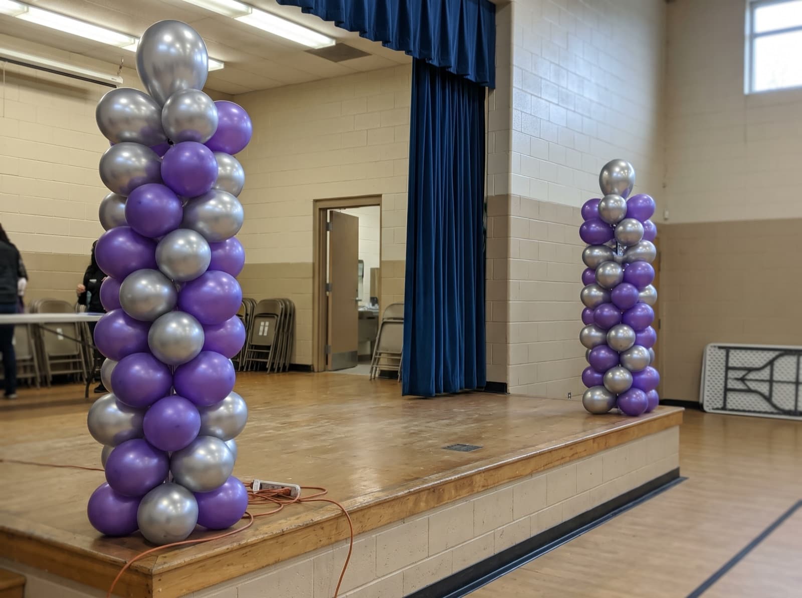 Tall purple and silver balloon columns at each end of a stage
