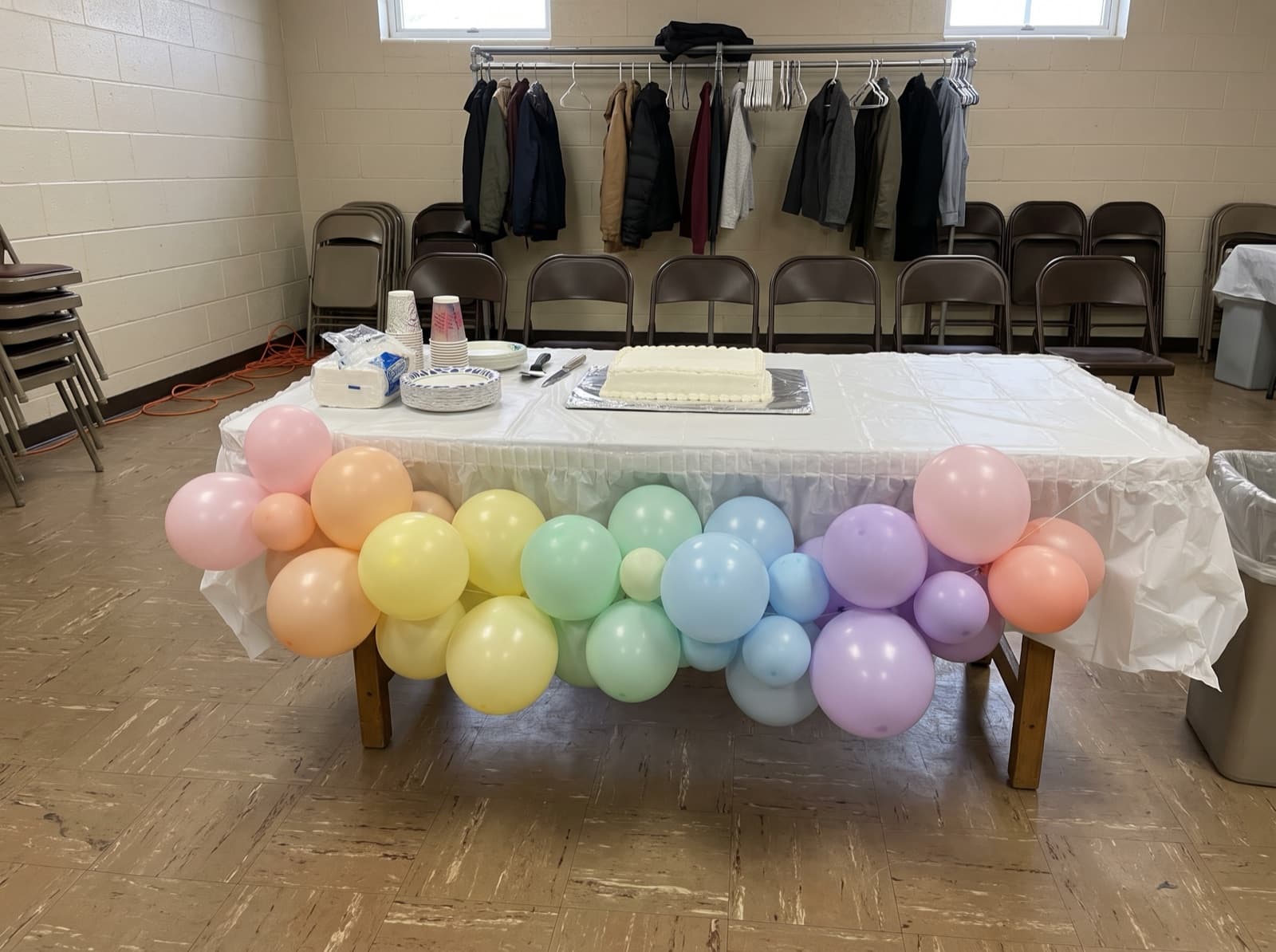 Pastel rainbow balloon garland across the front of a cake table