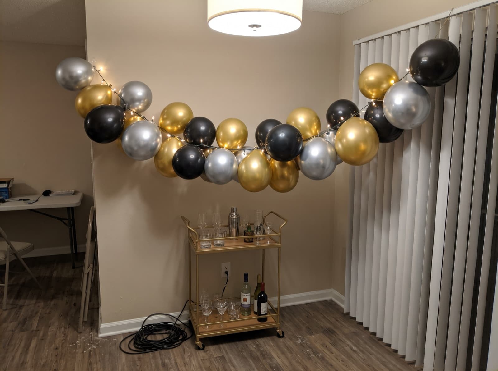 Chrome gold, silver and black balloon garland over a bar cart