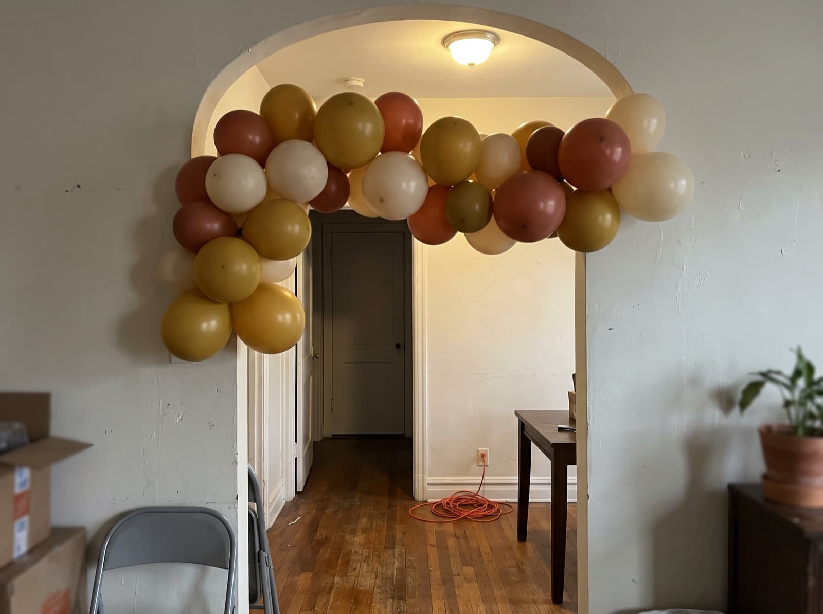 Mustard, rust and cream balloon garland around an arched doorway