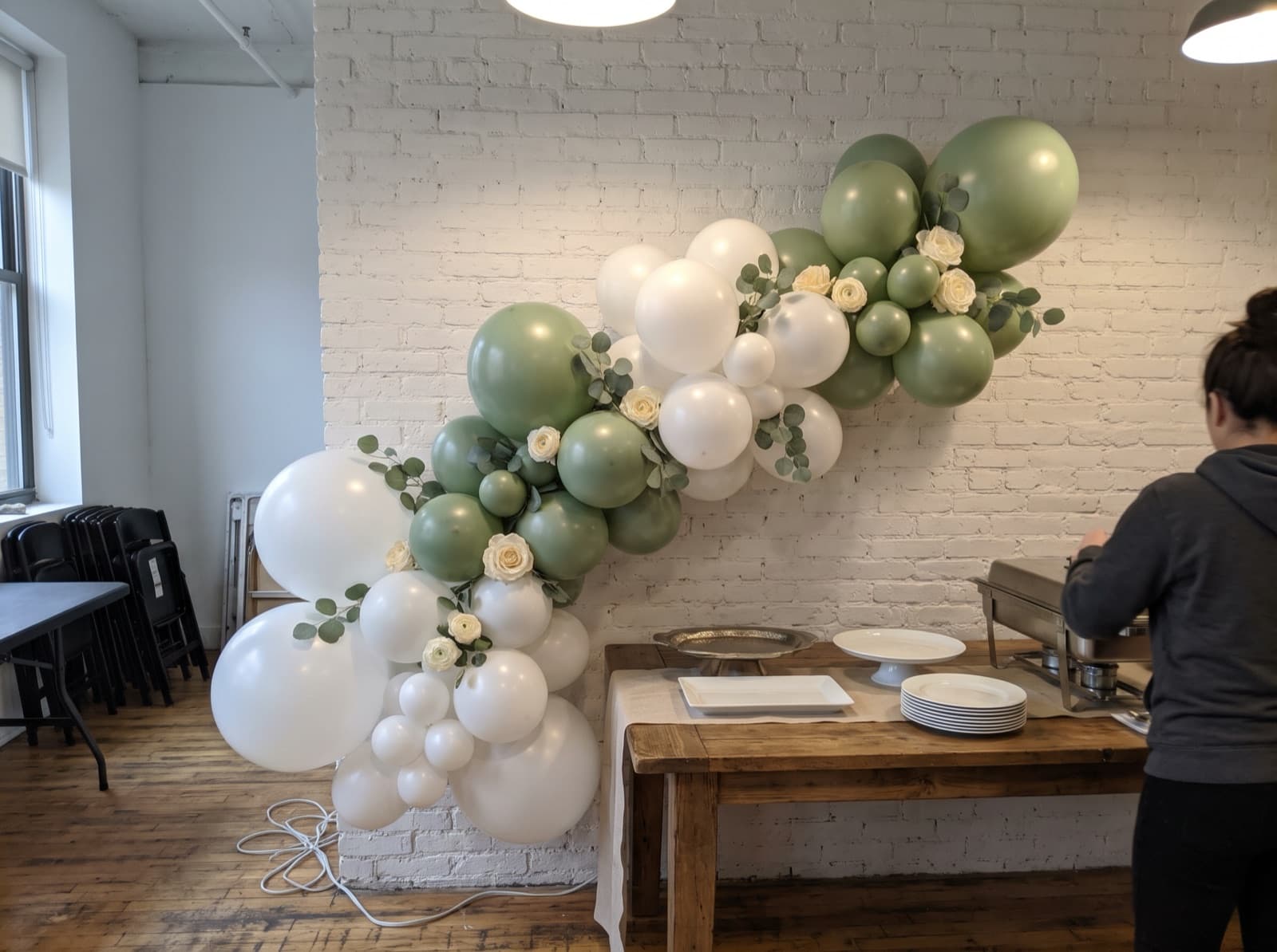 White and sage balloon garland with eucalyptus along a brunch buffet