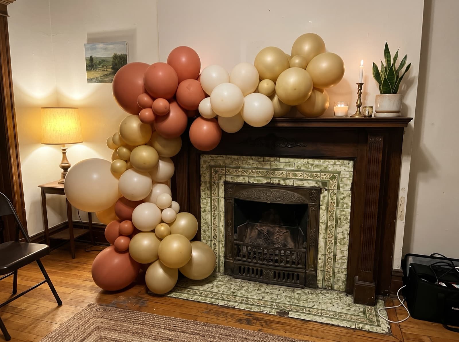 Organic balloon garland in terracotta, cream and gold across a tiled fireplace mantel in a Chicago apartment
