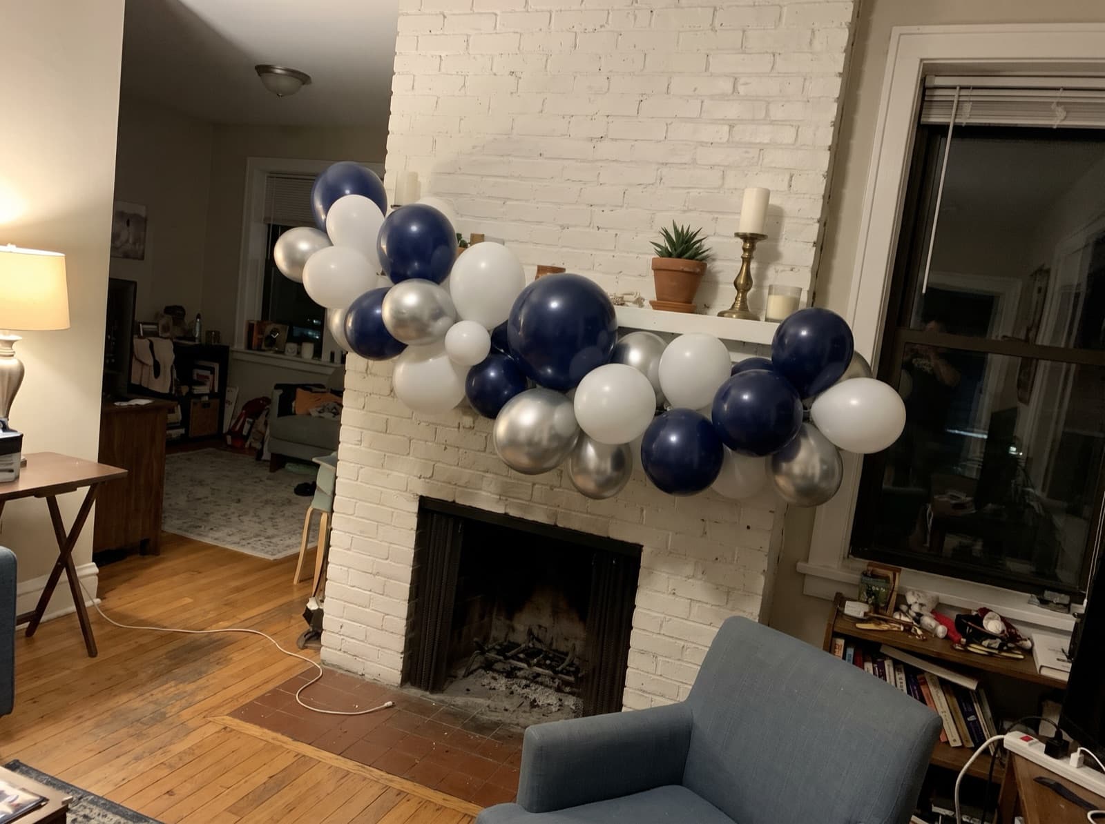 Navy, white and silver balloon garland on a painted brick fireplace mantel