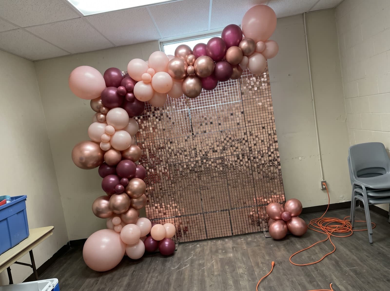 Blush and burgundy balloon garland over a rose gold shimmer wall