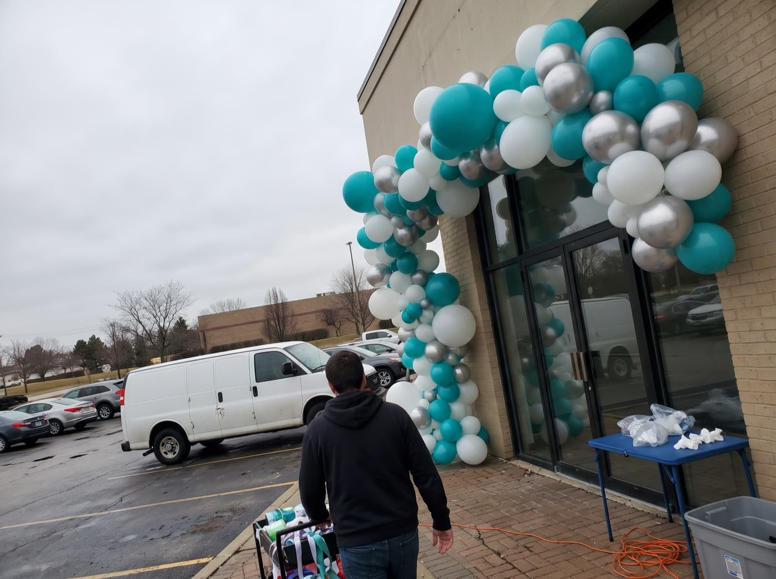Giant teal, white and silver balloon arch over a shop entrance