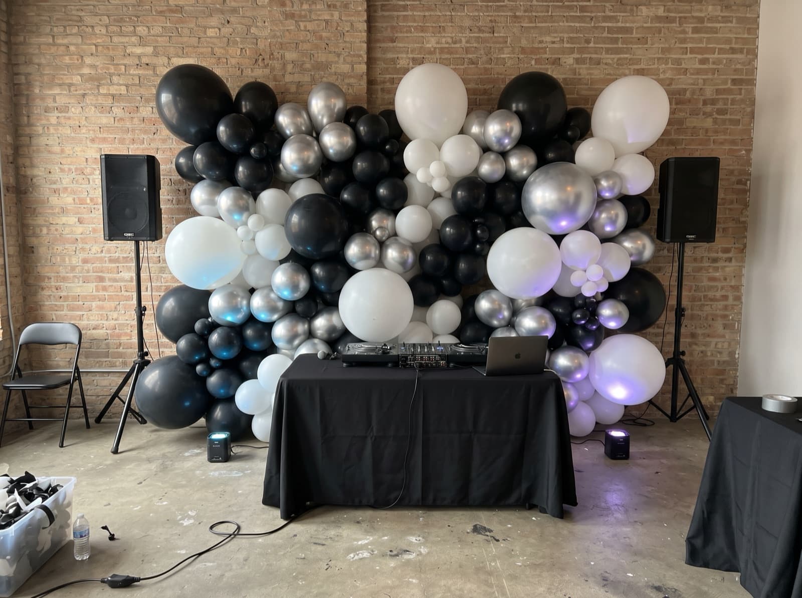 Black, silver and white balloon wall behind a DJ booth
