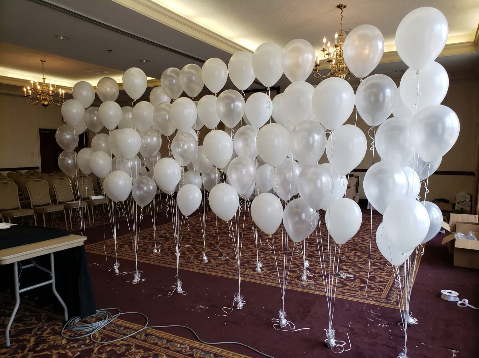 Floating helium balloon wall with ribbons in a ballroom
