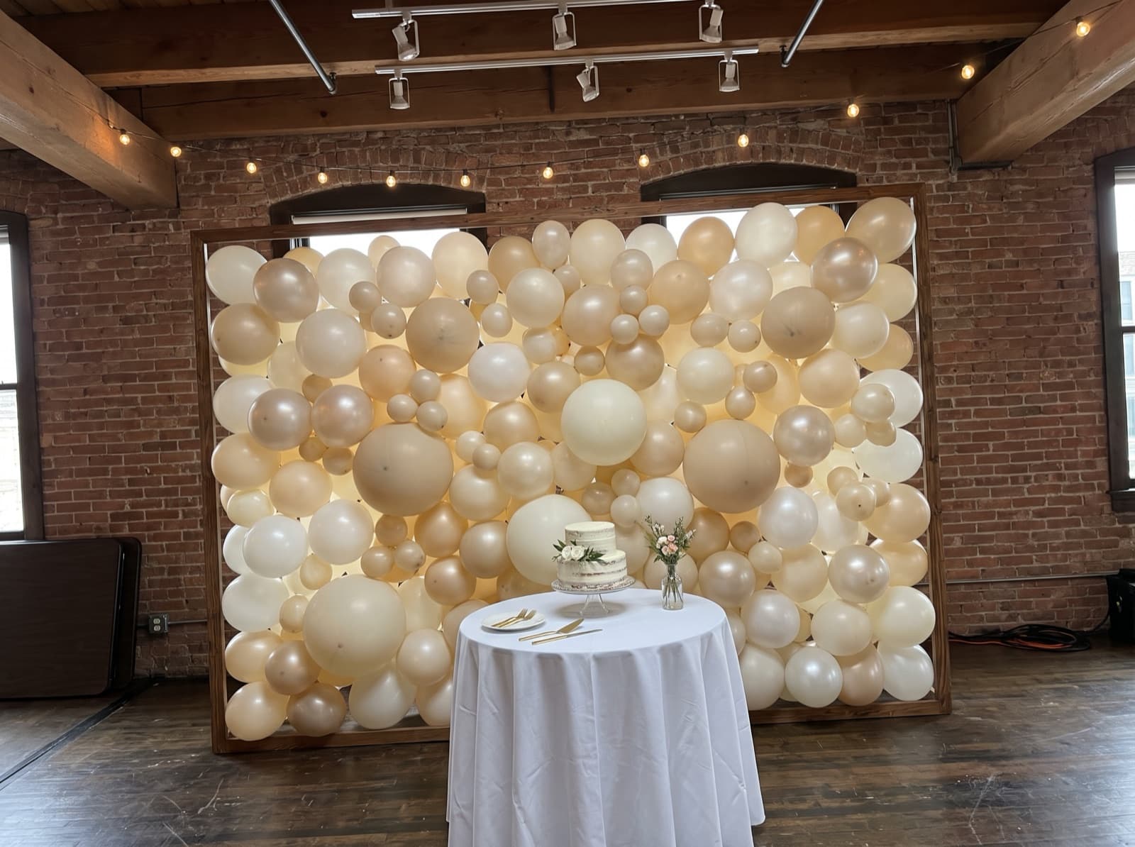 Organic balloon wall in ivory, champagne and pearl behind a sweetheart table in a Chicago loft venue